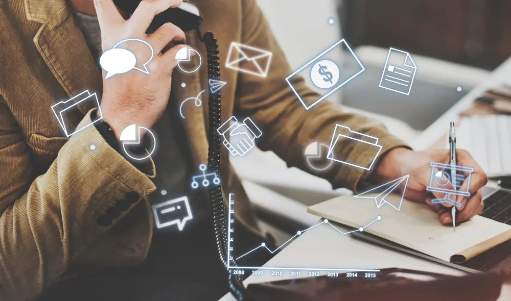 Torso de homem segurando telefone enquanto anota em caderno com ícones corporativos ilustrando integração VTEX
